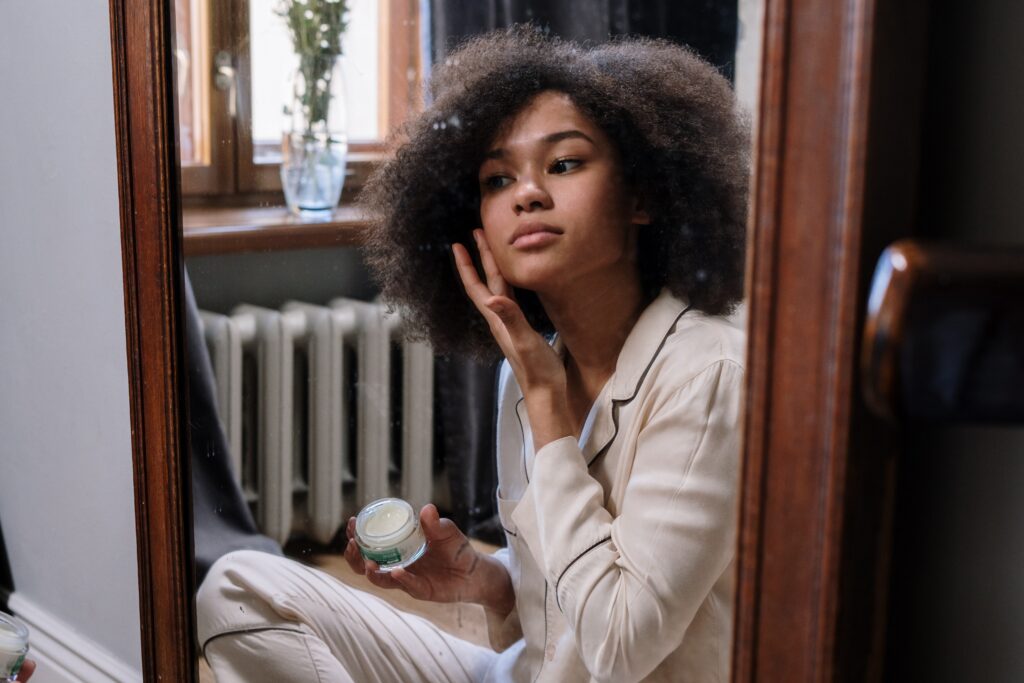 Bilden visar en person som applicerar en hudkräm eller ett ansiktsserum. Med naturlig hudvård och det bästa serumet så får du den bästa hudvårdsrutinen med den bästa handkrämen och bästa serum alternativt nyponrosolja samt naturlig hudvård för hela kroppen.